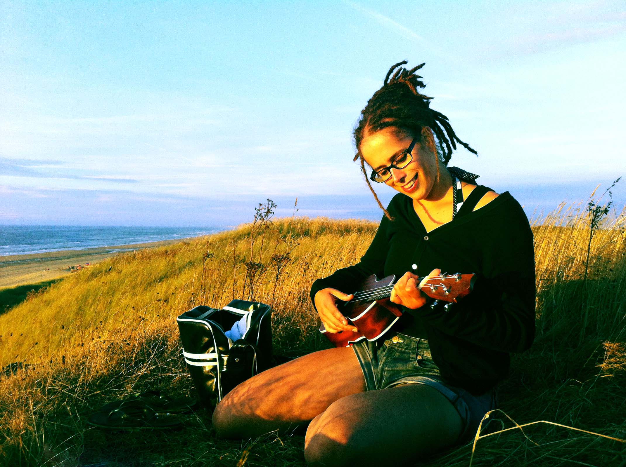 Claudia Hansen playing ukulele in the dunes at the beach